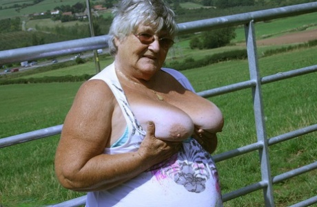 Old British woman Grandma Libby exposes herself next to a field of cattle